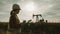 Woman engineer writing on clipboard in oil field. Female wearing white helmet and work clothes. Industrial, oil and gas