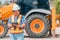 Woman Engineering wearing a white safety helmet standing In front of the backhoe And are using tablet to check the blueprint with