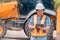 Woman Engineering wearing a white safety helmet standing In front of the backhoe And are using tablet to check the blueprint with