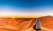 Woman enjoing sunrise in the Sahara desert next to M`hamid in Mo