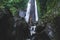 Woman enjoying near hidden in jungle cascade waterfall Dusun Kuning in Bali