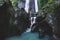 Woman enjoying near hidden in jungle cascade waterfall Dusun Kuning in Bali