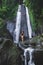 Woman enjoying near hidden in jungle cascade waterfall Dusun Kuning in Bali