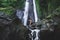 Woman enjoying near hidden in jungle cascade waterfall Dusun Kuning in Bali