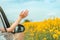 Woman enjoying ride in a car through countryside landscape in summer, hand reaching out the window