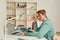 Woman enjoying study at home. Side view of young happy female student sitting at the table, reading handbook and