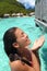 Woman enjoying water from outdoor shower showering in private overwater bungalow hotel in Tahiti, luxury spa resort