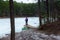 A woman enjoys a calm frozen lake located deep in the forest