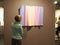 Woman enjoys a pastel-colored wavy artwork displayed during the Discovery Art Fair Frankfurt