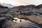 Woman enjoys a walk on a rock near the water. On the background a blurred snowy mountain. Norwegian fjord, Lofoten Islands