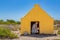 Woman entering yellow slave house at coast