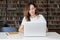 Woman entrepreneur working on laptop at co-working office or library, looks smart, bookshelves. Knowledge and self-development