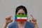 A woman with Equatorial guinea flag on hygienic mask in her hand and lifted up the front face on beige color background. Tiny