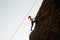 Woman equipped with a rope climbing on the sloping rock