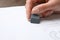 Woman erasing word on sheet of white paper at table, closeup