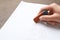 Woman erasing word on sheet of white paper at wooden table, closeup