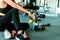 Woman exercise in gym fitness breaking and relax. hand  holding apple fruit after training sport and dumbbell, water bottle on the