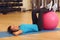 Woman exercising her abs on a pink Pilates ball indoors