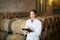 Woman expert wearing coat standing in large wine cellar