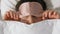 Woman with eye sleeping mask in bed under blanket