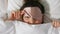 Woman with eye sleeping mask in bed under blanket