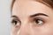 Woman during eyebrow tinting procedure on grey, closeup