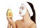 Woman with face clay mask holding avocado.