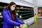 Woman with face mask buying lettuce at store with empty shelves