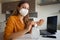 Woman with face mask FFP2 KN95 working from home with laptop and using hand alcohol gel or sanitizer against corona virus Covid-19