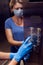 Woman with face medical mask and gloves doing disinfection of buttons in elevator. Hygiene and health protection concept