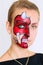 Woman face with painted devil mask on it on white background