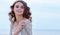 Woman face Portrait on the beach. Happy beautiful curly-haired girl close-up, the wind fluttering hair. Spring portrait on the bea