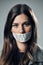 Woman, face and protest with mouth tape in Russia for cold war, armageddon or doomsday against a gray studio background