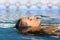 Woman face relaxing floating on water of a pool or spa