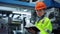 Woman factory worker looking camera near big metal manufacture constructions.