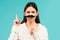 Woman with fake mustache having fun. Funny female actress with finger up  on blue background.