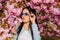 Woman fancy sunglasses in spring flower bloom. Girl in cherry blossom flower. Spring fashion collection. Sakura tree