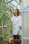 woman farmer or agronomist in light apron in garden with wicker basket of red tomatoes