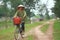 A woman farmer is biking home from her work on the paddy field