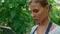 Woman farmer checking plants quality with digital tablet in garden closeup.