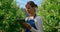 Woman farmer collecting data with modern device in green plantation smiling