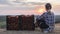 Woman farmer sitting near boxes with tomatoes, admiring the beautiful landscape, resting after work