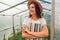 Woman farmer standing in greenhouse. Happy worker growing vegetables and proud of her work in hothouse