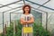 Woman farmer standing in greenhouse. Happy worker growing vegetables working in hothouse. Agriculture