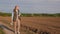 A woman farmer walks along a country road among plowed fields