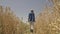 woman farmer walks through field with wheat rubber boots. slow motion. back view. farming wheat concept. technology