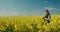 Woman farmer working in a picturesque field of blooming rapeseed