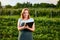 Woman farmer working in a strawberry field. Biologist inspector examines strawberry bushes