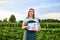 Woman farmer working in a strawberry field. Biologist inspector examines strawberry bushes and shows the level of crop growth usin