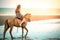 Woman fashion model riding a horse on the beach.